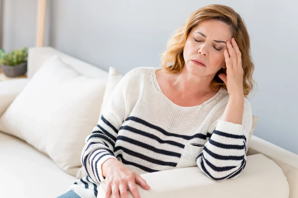 woman suffering from headache dealing with challenges of elderly parent care