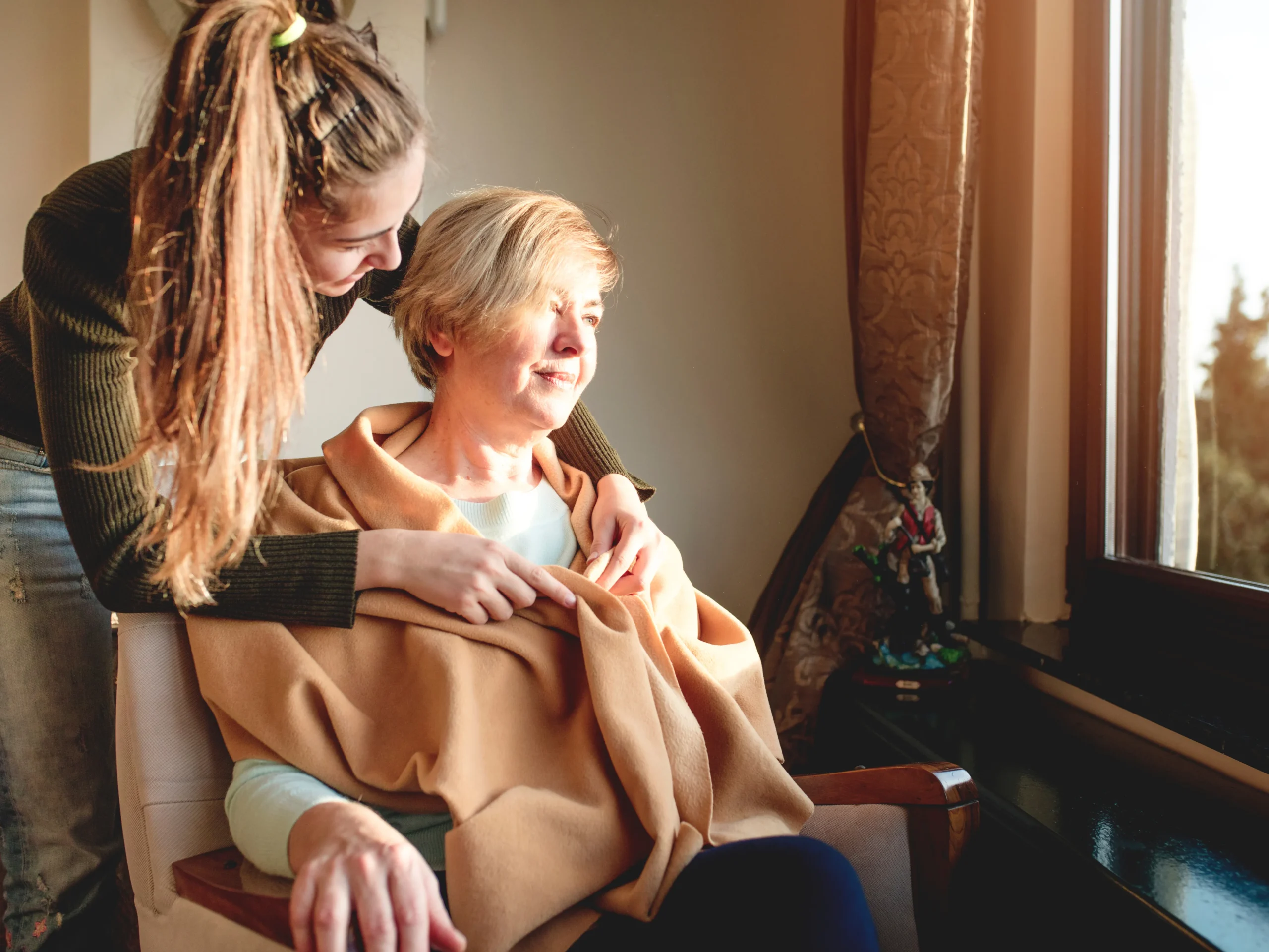 woman putting jacket on elderly parent